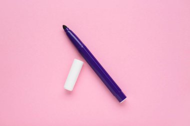 Bright purple marker and cap on light pink background, flat lay