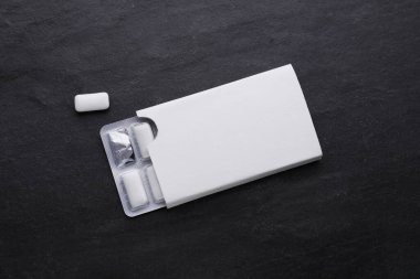 Blister with chewing gums on black table, flat lay