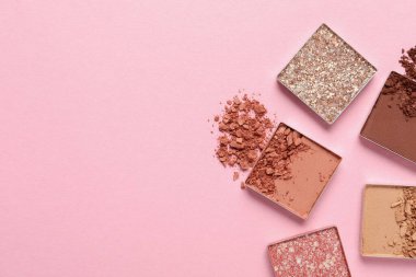 Crushed eye shadows on pink background, flat lay with space for text. Professional makeup product
