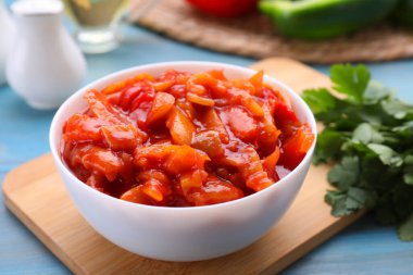 Bowl of delicious lecho on light blue wooden table, closeup