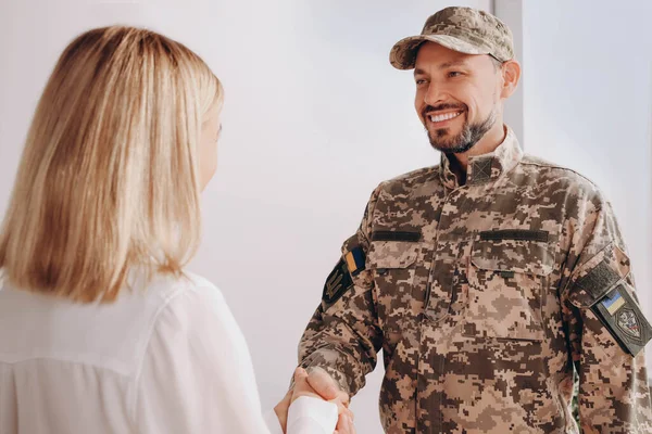 Psychologist shaking hands with military officer in office