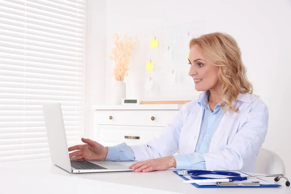Doctor with laptop consulting patient in clinic. Online medicine concept