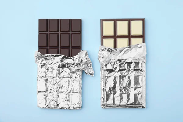 Tasty chocolate bars on light blue background, flat lay