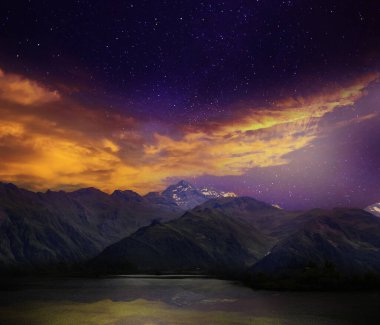 Fantastic sky with many stars and beautiful clouds over mountains