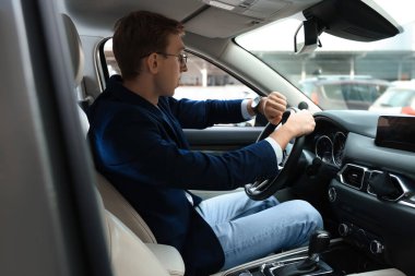 Young man checking time in car. Being late