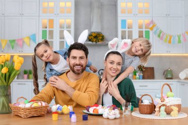 Portrait of happy family and Easter eggs at table in kitchen