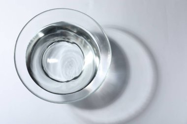 Beyaz arka planda su olan cam kase, üst manzara.