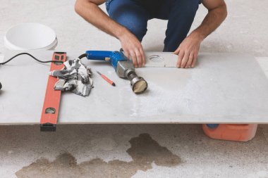 Worker making socket hole in tile indoors, closeup