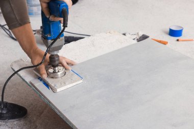 Worker making socket hole in tile indoors, closeup