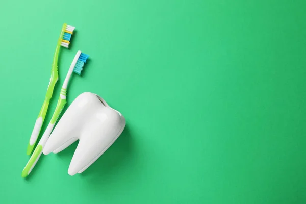 Toothbrushes and holder on green background, flat lay. Space for text
