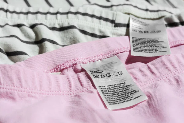 Clothing labels with instructions on garments, closeup