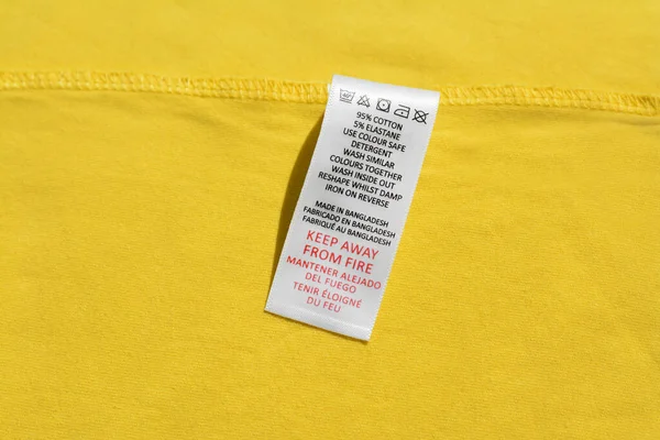 Clothing label on yellow garment, top view