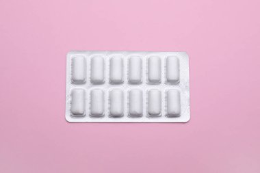 Blister with chewing gums on pink background, top view