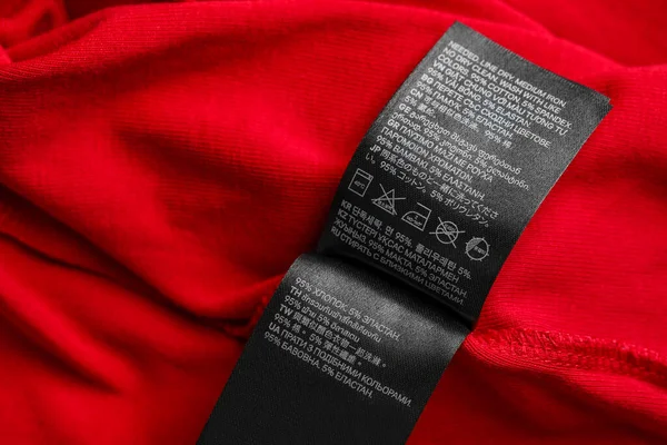 Black clothing labels on red garment, top view