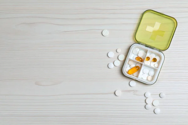 Pill box with medicaments on white wooden table, flat lay. Space for text