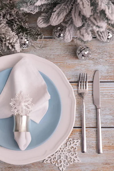 Festive place setting with beautiful dishware, cutlery and fabric napkin for Christmas dinner on light blue wooden table, flat lay
