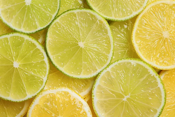 Slices of lemon and lime as background, top view