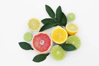 Different citrus fruits and leaves on white background, top view