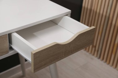 Stylish desk with open empty drawer in office
