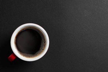 Cup with aromatic coffee on black background, top view. Space for text