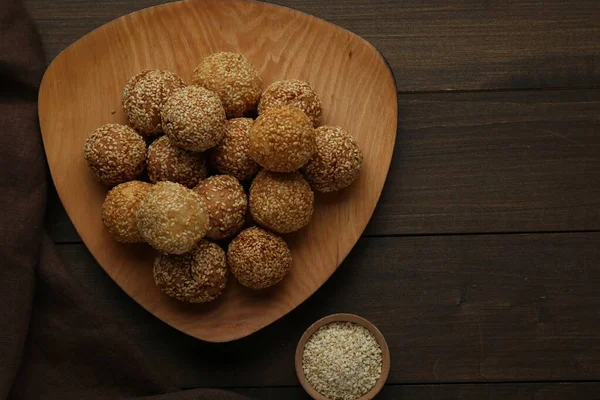 Delicious sesame balls on wooden table, flat lay. Space for text