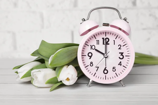 Pink Alarm Clock Beautiful Tulips White Wooden Table Brick Wall — Stok fotoğraf
