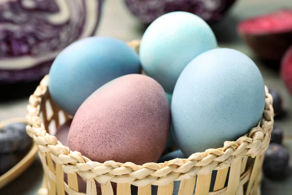 Colorful Easter eggs painted with natural dyes in wicker bowl, closeup