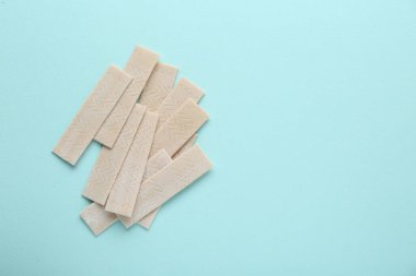 Many sticks of tasty chewing gum on light blue background, flat lay. Space for text