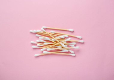 Heap of wooden cotton buds on pink background, flat lay