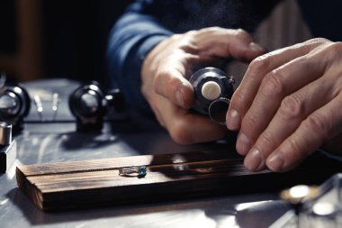 Professional jeweler working with ring at table, closeup
