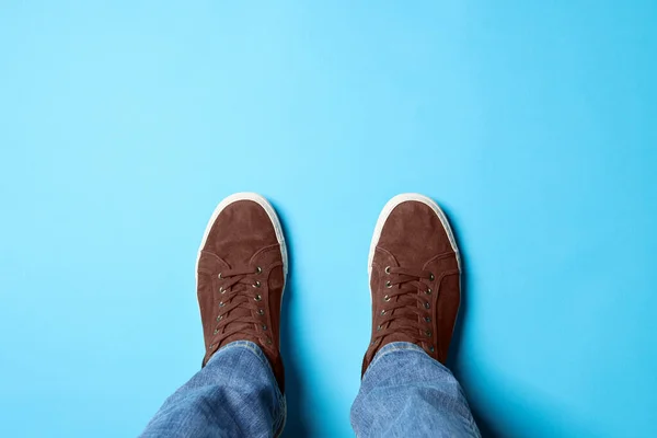 Man in brown shoes standing on light blue background, top view