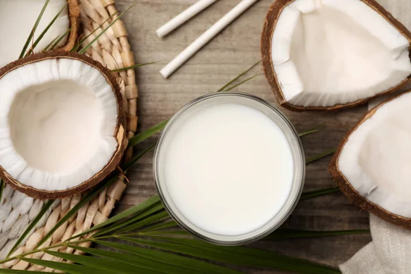 Glass of delicious vegan milk and coconuts on wooden table, flat lay