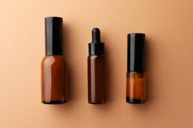 Bottles of face cream on beige background, flat lay