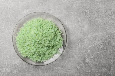 Glass plate with natural sea salt on light grey table, top view. Space for text