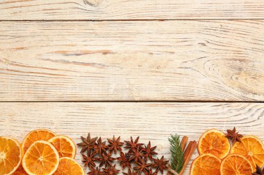 Dry orange slices, cinnamon sticks and anise stars on white wooden table, flat lay with space for text