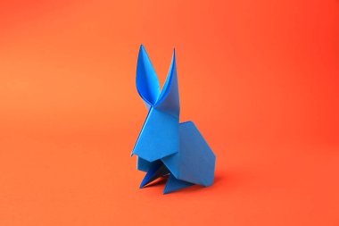 Origami art. Beautiful paper rabbit on orange background