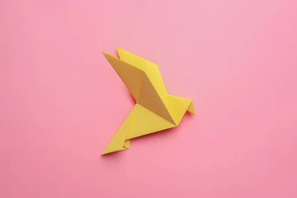 Beautiful yellow origami bird on pink background, top view