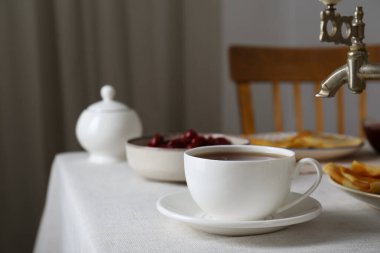 Vintage samovar, cup of hot drink and snacks served on table indoors. Traditional Russian tea ceremony