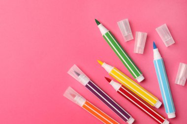 Many bright markers on pink background, flat lay. Space for text