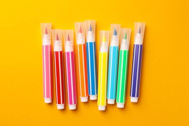 Many bright markers on yellow background, flat lay