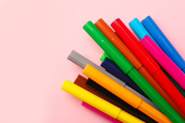 Many bright markers on pink background, flat lay. Space for text