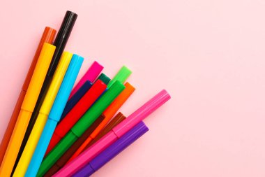 Many bright markers on pink background, flat lay. Space for text