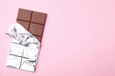 Tasty chocolate bar on pink background, top view. Space for text