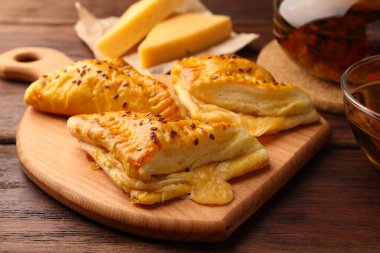 Fresh delicious puff pastry with cheese on wooden table, closeup