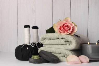 Composition with different spa products, rose and candle on white table against wooden background
