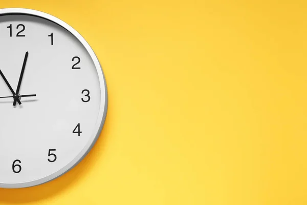 Stylish round clock on yellow background, top view with space for text. Interior element