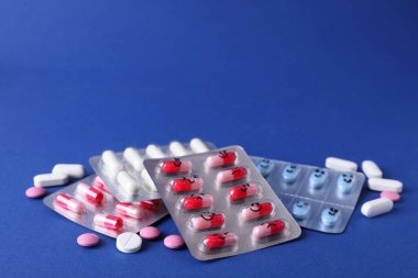 Blisters of different antidepressants with emoticons on blue background