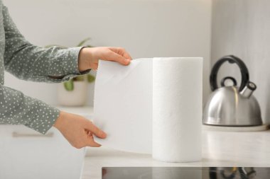 Woman tearing paper towels in kitchen, closeup