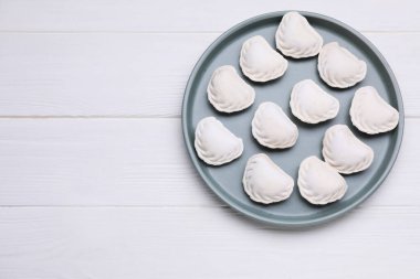 Raw dumplings (varenyky) on white wooden table, top view. Space for text