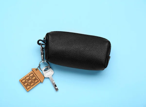 Leather case with keys on light blue background, top view